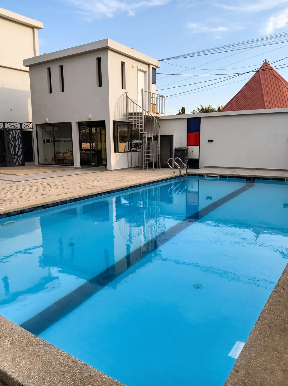 La piscine reflétant le bâtiment blanc de la résidence et son escalier en colimaçon
